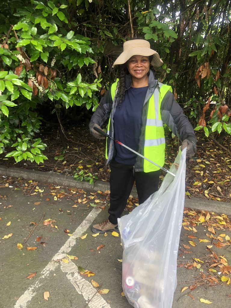 Josephine picking up litter with a yellow vest and bag full of collected litter